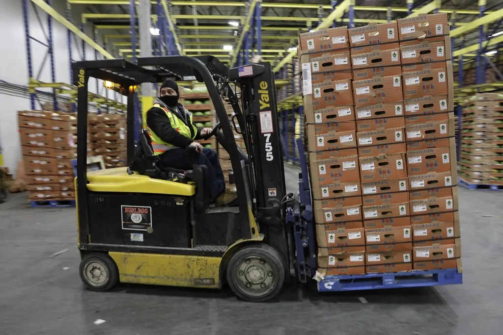 Cariste déplaçant une palette de cartons dans un entrepôt