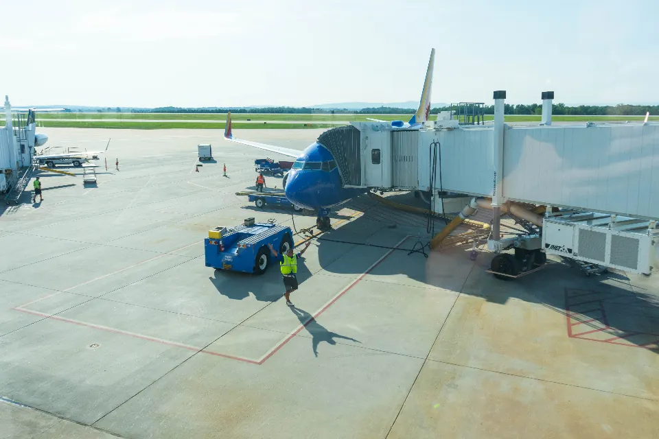 Avion à la porte d'embarquement, entouré de véhicules de piste